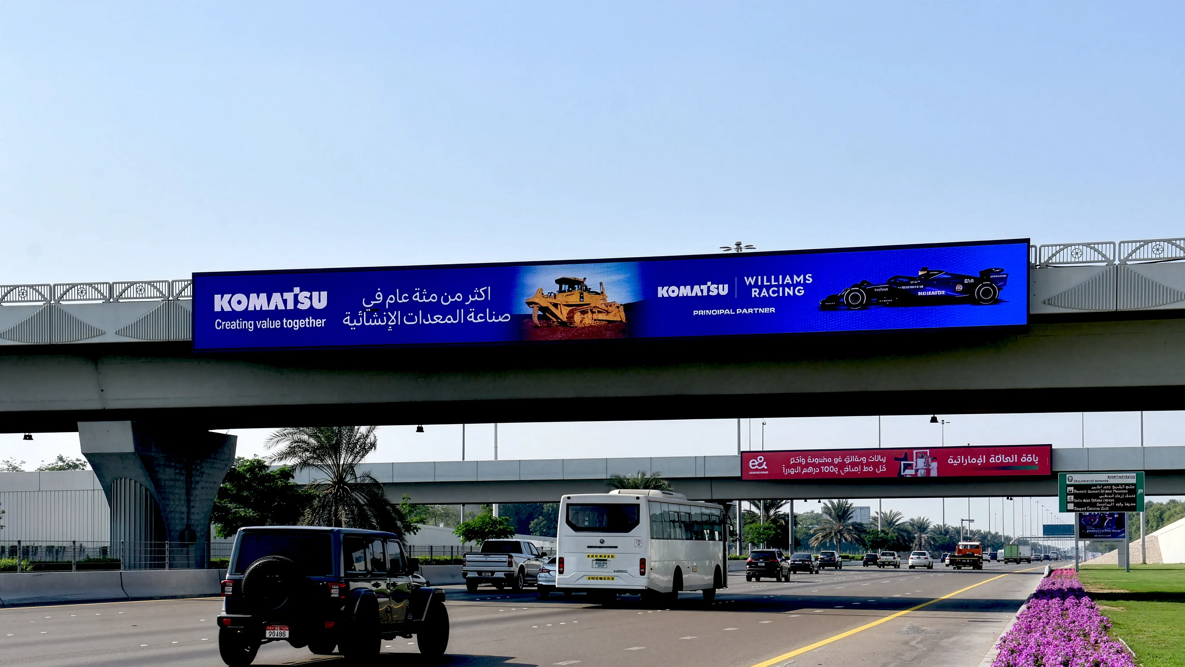 Komatsu bridge banner advertising on Sheikh Zayed Road, Dubai — large-format overpass billboard featuring Komatsu construction equipment and Williams Racing partnership branding, high-impact highway outdoor advertising.